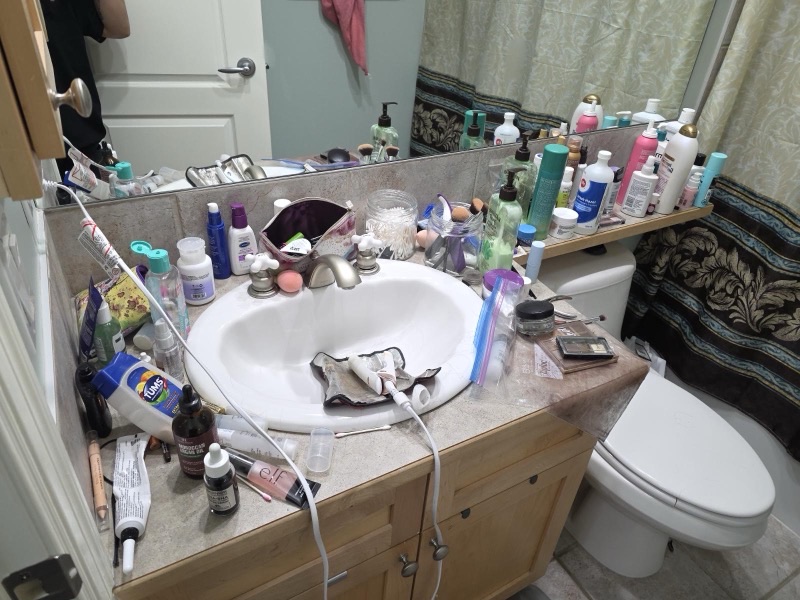 Cluttered bathroom vanity before NeatNow cleaning service in Calgary