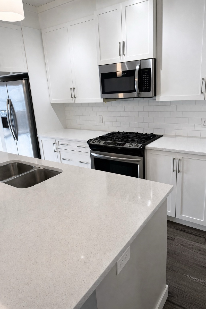 White kitchen with spotless quartz counters, clean stovetop, and gleaming appliance exteriors after a NeatNow first time clean in Calgary