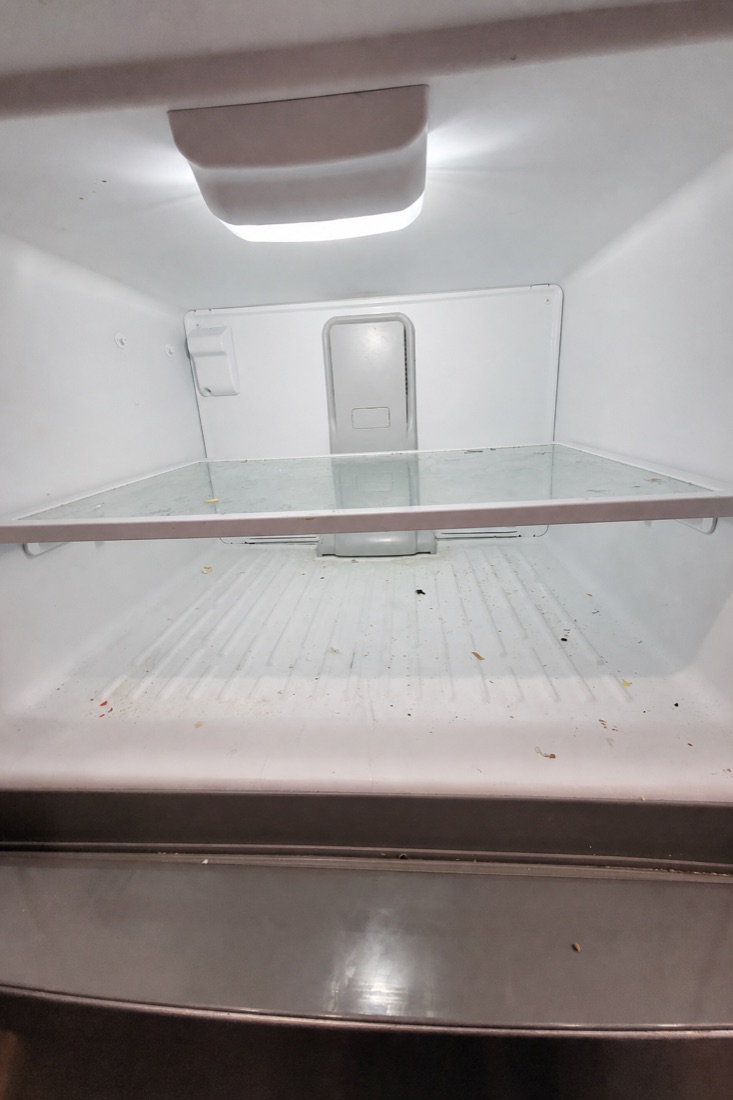 Before photo of a freezer interior with frost build-up and spills, before a NeatNow clean