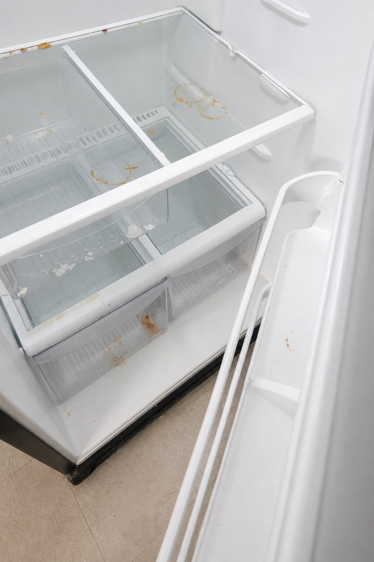 Before photo of a refrigerator interior with food residue and stained shelves, before a NeatNow clean in Calgary